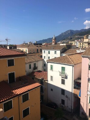 A view of a densely packed urban area with terracotta-tiled buildings, a prominent clock tower, and a mountain backdrop. - Casa Maria (Salerno)