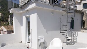 A rooftop terrace with a white chair, a metal ladder, and a small white structure. - Casa Maria (Salerno)