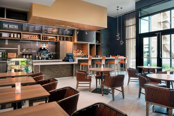 A modern bistro with a bar area, seating, and a large window offering a view of the city. - Courtyard Phoenix Downtown (Phoenix)