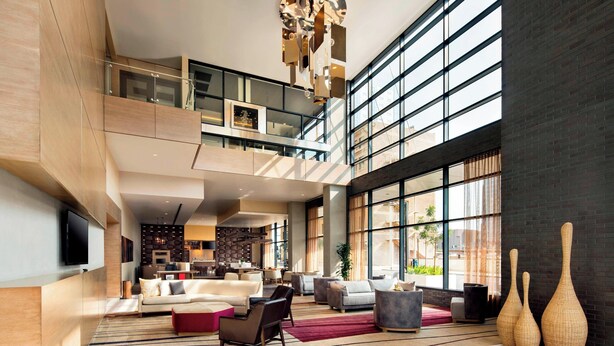 A spacious living area with a high ceiling, large windows, and a modern chandelier. - Courtyard Phoenix Downtown (Phoenix)