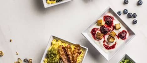 Diversos platos de desayuno en recipientes sobre una superficie de mármol.