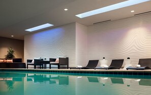 A modern indoor pool area with lounge chairs and a dining table. - Residence Inn Phoenix Downtown (Phoenix)