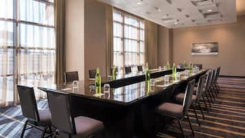 A conference room with a long table, chairs, and a carpeted floor.