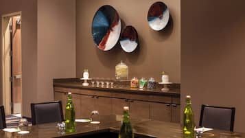 Un salón de conferencias con una larga mesa, sillas, un mostrador de buffet con comida y bebidas, y decoración en las paredes.