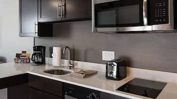 A modern kitchen with dark cabinets, a stainless steel microwave, a coffee maker, a toaster, and a dishwasher.