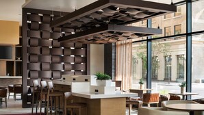 Un espace bar moderne doté d’un plafond au design géométrique original, d’un comptoir central et de différents types de sièges.