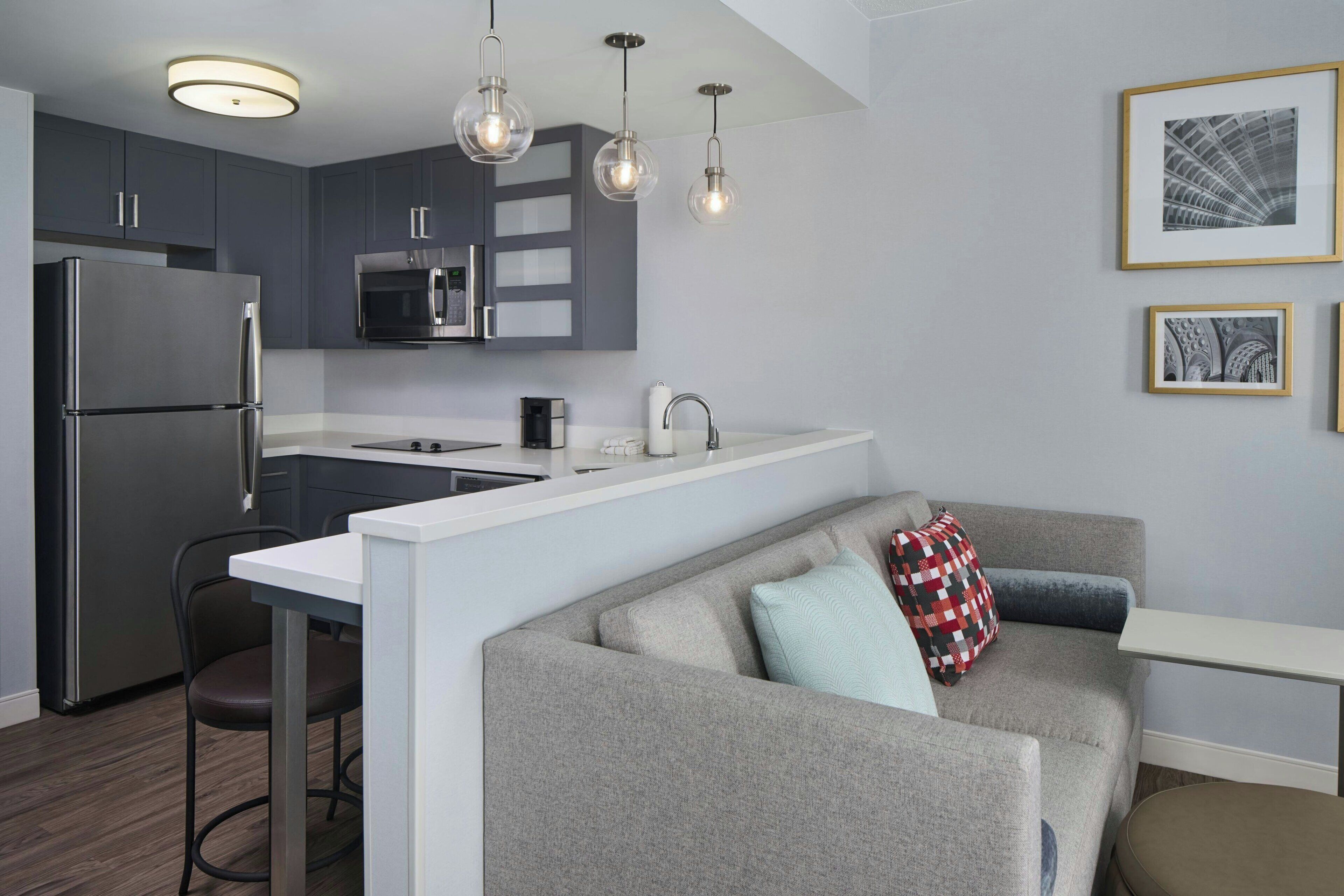 A modern kitchen with a built-in microwave, stainless steel refrigerator, and pendant lighting.