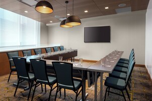 Un salón de conferencias con una larga mesa, sillas e iluminación suspendida.