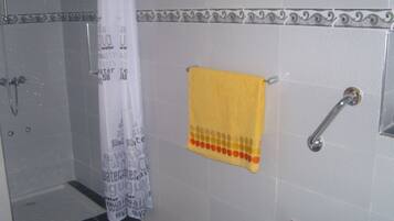 Un baño con ducha, un perchero y una toalla amarilla, además de una cortina de ducha con texto alusivo al agua.
