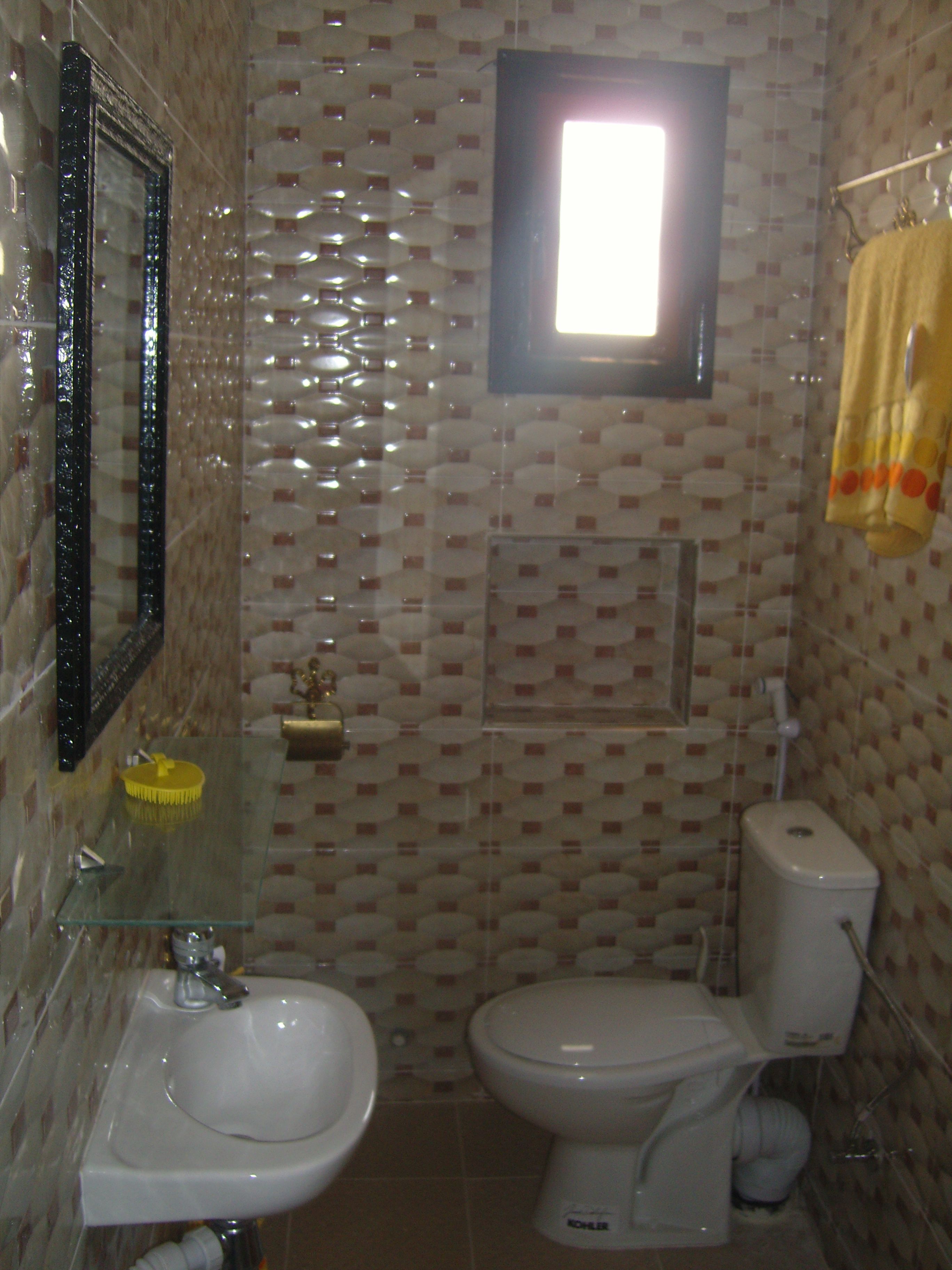 Un baño con un lavamanos de vidrio, un inodoro y un espejo.