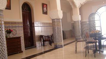 A room with a tiled floor, a wooden door, a chair, and a table.