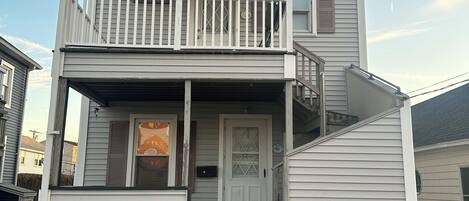 A two-story house with a balcony, a front door, and a small porch.