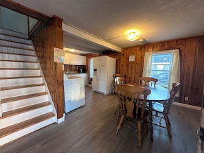 A wooden interior with a kitchen, dining area, and staircase. - Nautical Beach Properties (Hampton)