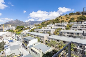 A residential area with modern buildings, solar panels, and a mountainous backdrop.