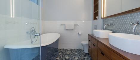 Une salle de bain moderne avec une douche à parois de verre, une baignoire sur pieds, deux vasques et des toilettes.