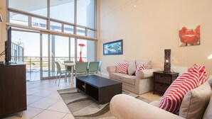 A modern living room with a large window, a sofa set, a coffee table, and a TV on a wooden cabinet.