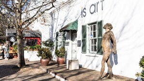 Un bâtiment sur lequel est apposée une enseigne indiquant « ceci est de l’art », et une statue d’un homme devant.