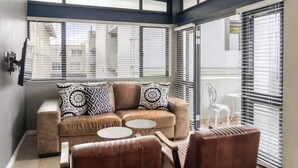 Ein modernes Wohnzimmer mit einer Couch, zwei runden Couchtischen und einem braunen Ledersessel.