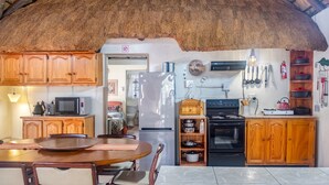 Una cucina con mobili in legno, un frigorifero, un forno a microonde, un fornello e un'area pranzo con tavolo e sedie.