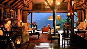 A cozy room with a large window, wooden furniture, and a warm ambiance. - Tanamera Lodge (Sabie)