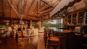 A rustic bar area with wooden furniture, a bar counter, and a view of the outdoors. - Tanamera Lodge (Sabie)