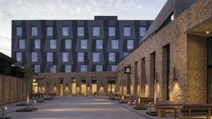 A modern hotel courtyard with a central open space, stone walls, and multiple windows.