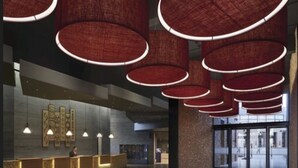 A modern lobby with a reception desk, pendant lighting, and a large glass entrance.