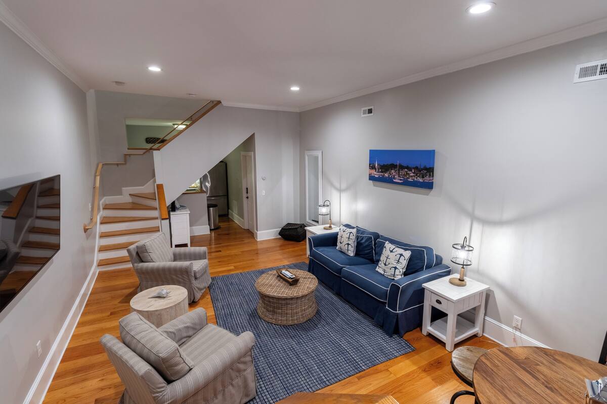 Ein modernes Wohnzimmer mit Treppe, einem blauen Sofa und einem runden Couchtisch.