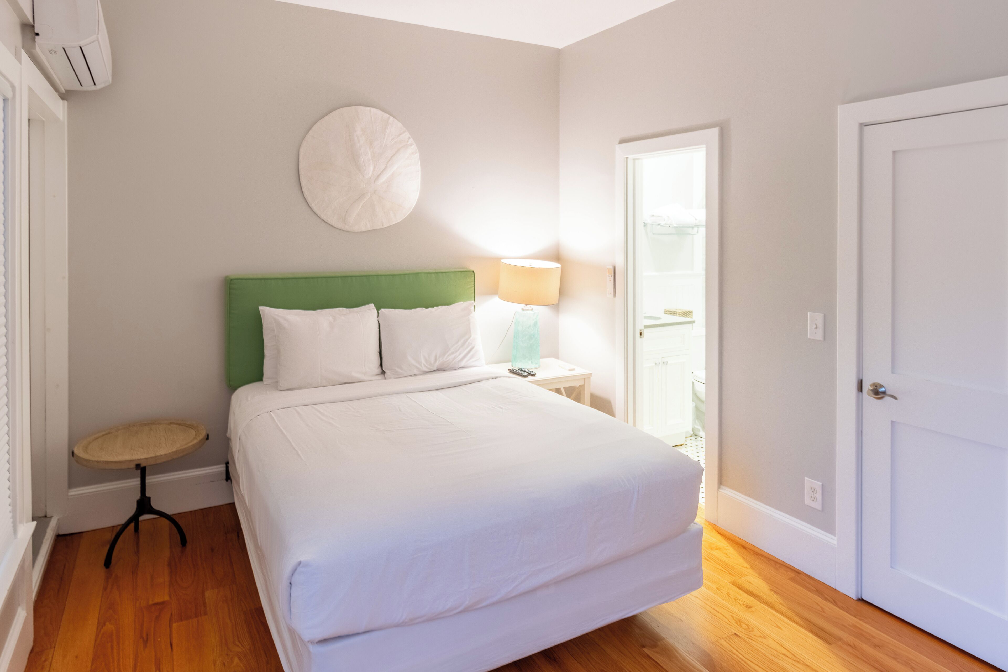 A bedroom with a bed, a round wall decoration, a bedside lamp, a small table, and a door.