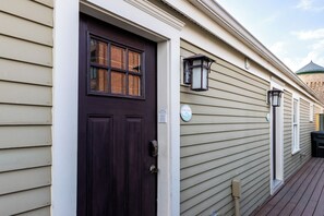 A house with a dark brown front door, beige siding, and a small porch with a light fixture. - The Newport Lofts - 359 Thames Street (Newport)
