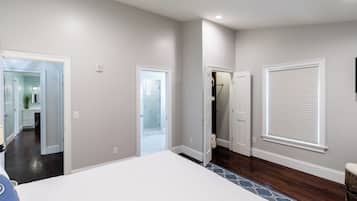 Un dormitorio con una cama grande, un vestidor y un baño visible a través de una puerta abierta.