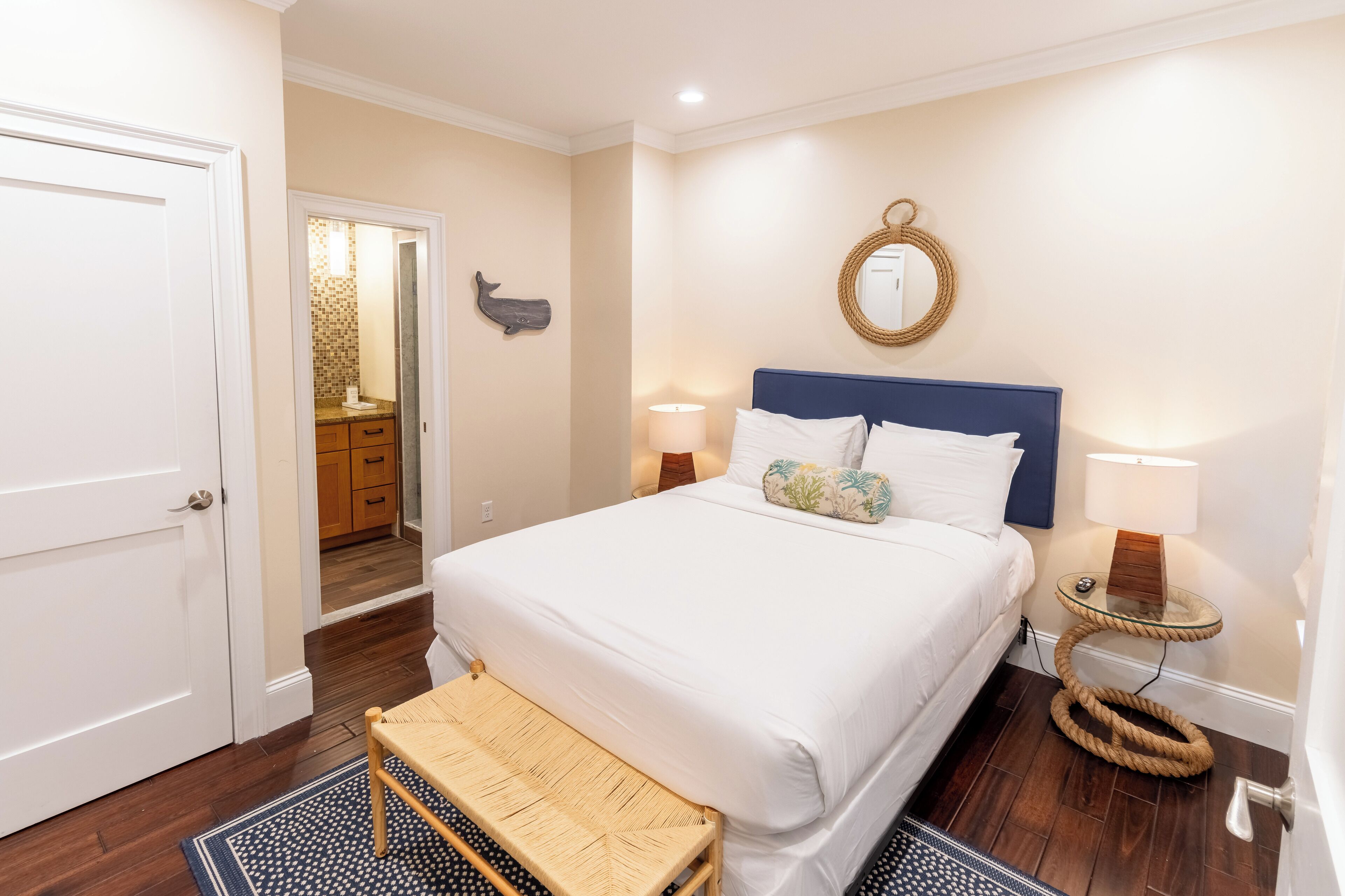 Un dormitorio con cama, lámparas de noche, un espejo y una mesita.