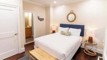 Un dormitorio con cama, lámparas de noche, un espejo y una mesita.