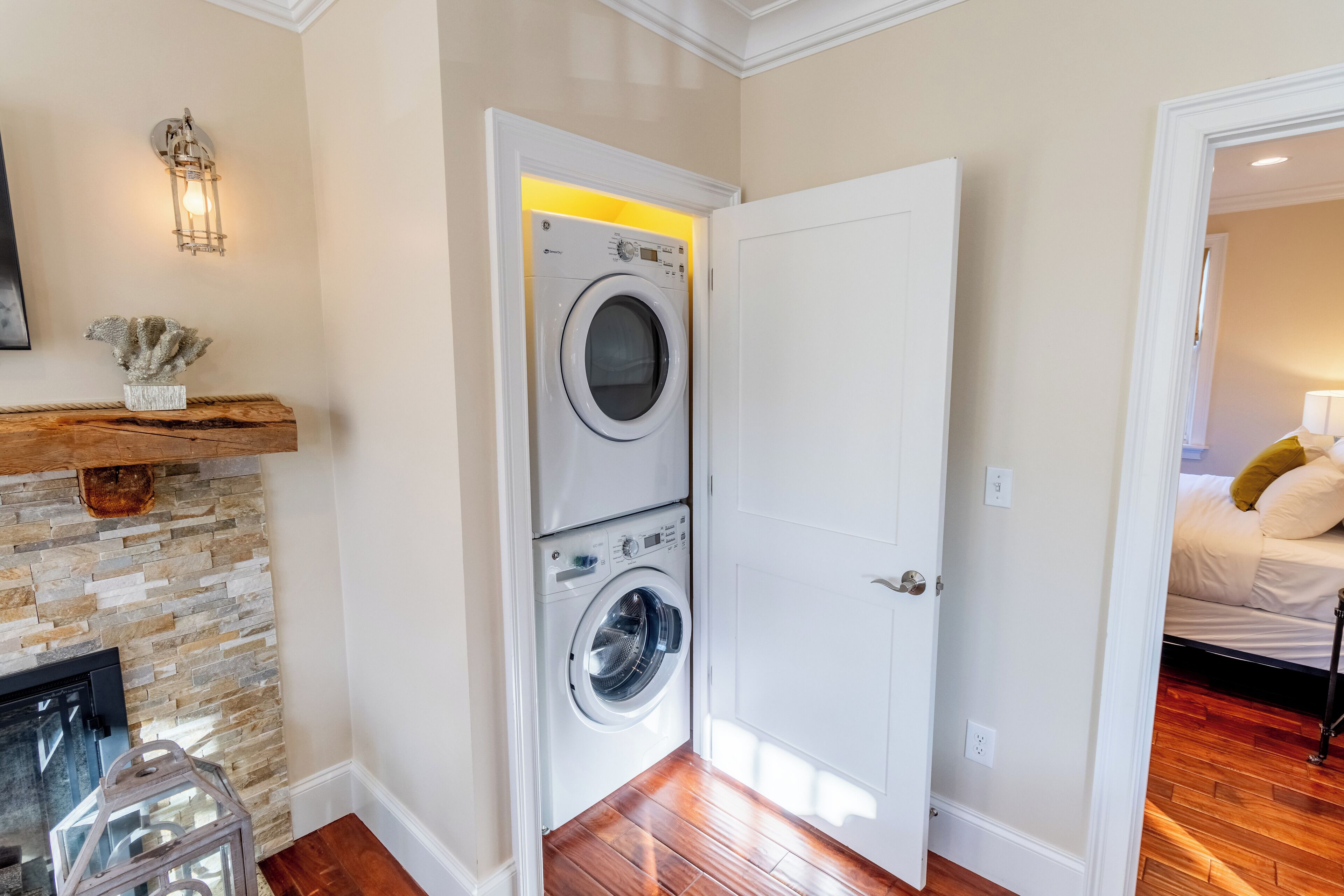 A laundry room with a washing machine and dryer, a stone wall, and a wooden floor.