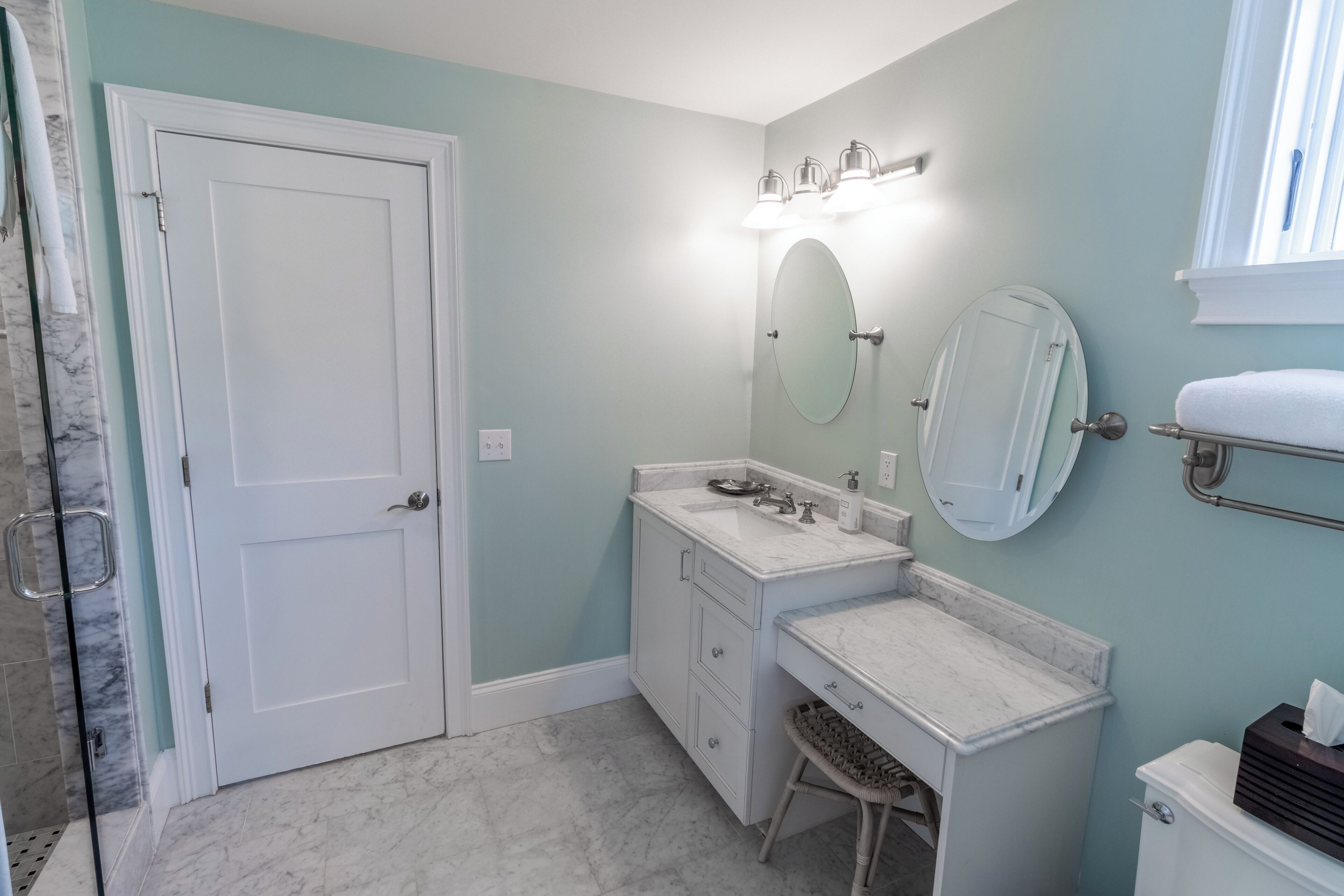 A bathroom with a white vanity, a large mirror, a toilet, and a shower area.
