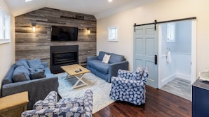 Una sala de estar moderna con chimenea, televisor grande y puerta corrediza.