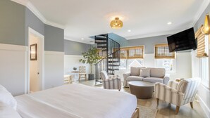 Une chambre moderne avec un grand lit, un escalier en colimaçon, un canapé et un téléviseur.