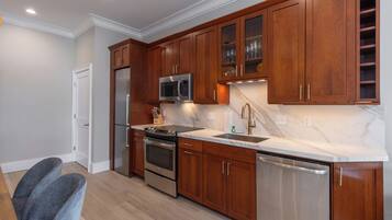A modern kitchen with wooden cabinets, stainless steel appliances, and a marble countertop.