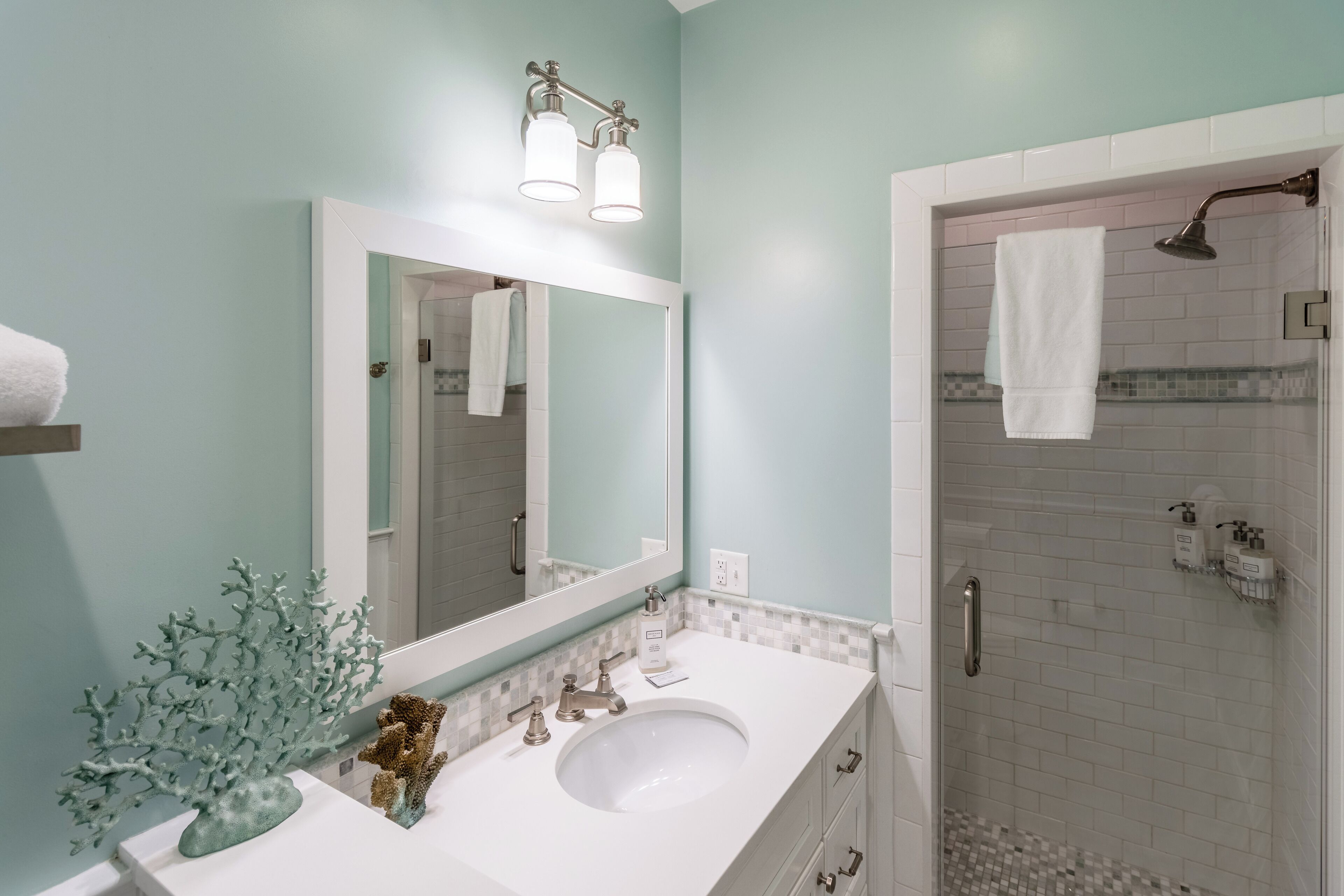 A bathroom with a white sink, a large mirror, and a shower area.