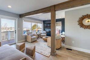 A spacious living area with a balcony, wicker furniture, and a large wall-mounted mirror. - The Newport Lofts - 617 Thames Street (Newport)