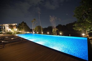 Una piscina al aire libre, sillones reclinables de piscina