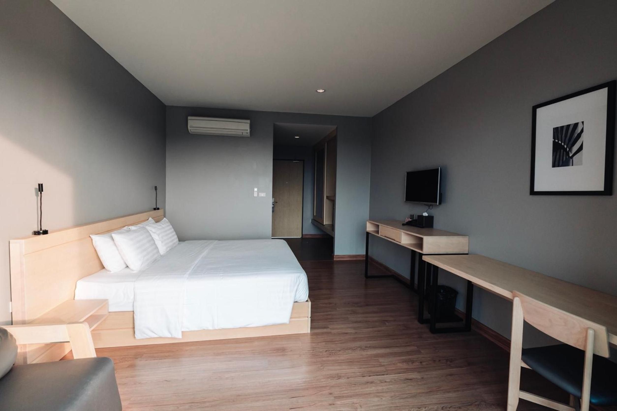 Een moderne hotelkamer met een bed, bureau, stoel en een televisie.