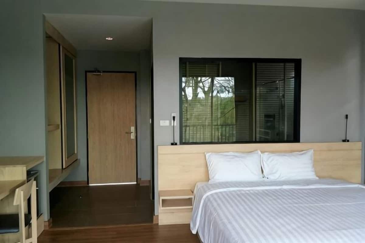 A bedroom with a bed, a wooden headboard, a window, and a door.