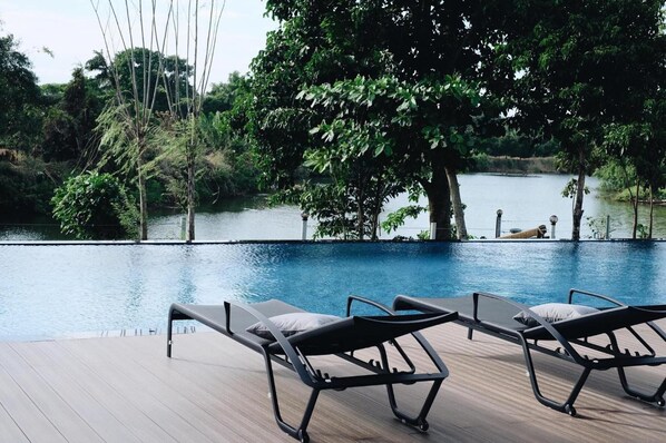 Una piscina al aire libre, sillones reclinables de piscina