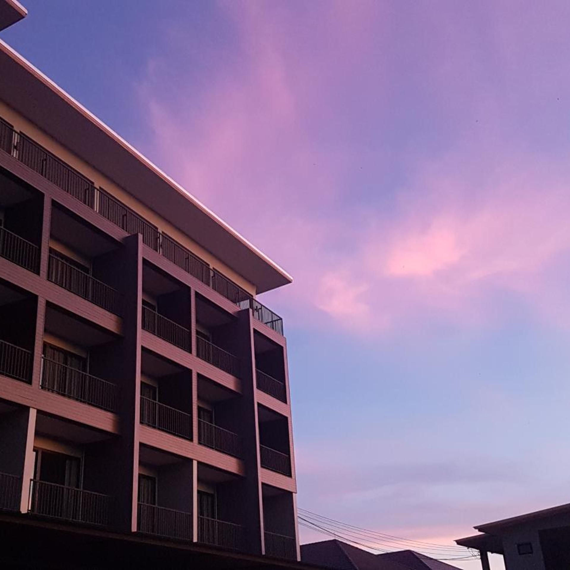 Un edificio de varios pisos con balcones, bajo un cielo despejado.