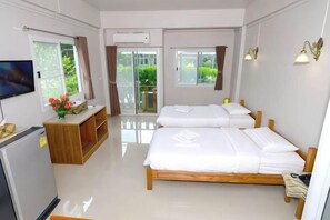 Une chambre d’hôtel avec deux lits, une télévision, un bureau et un balcon donnant sur un espace verdoyant.