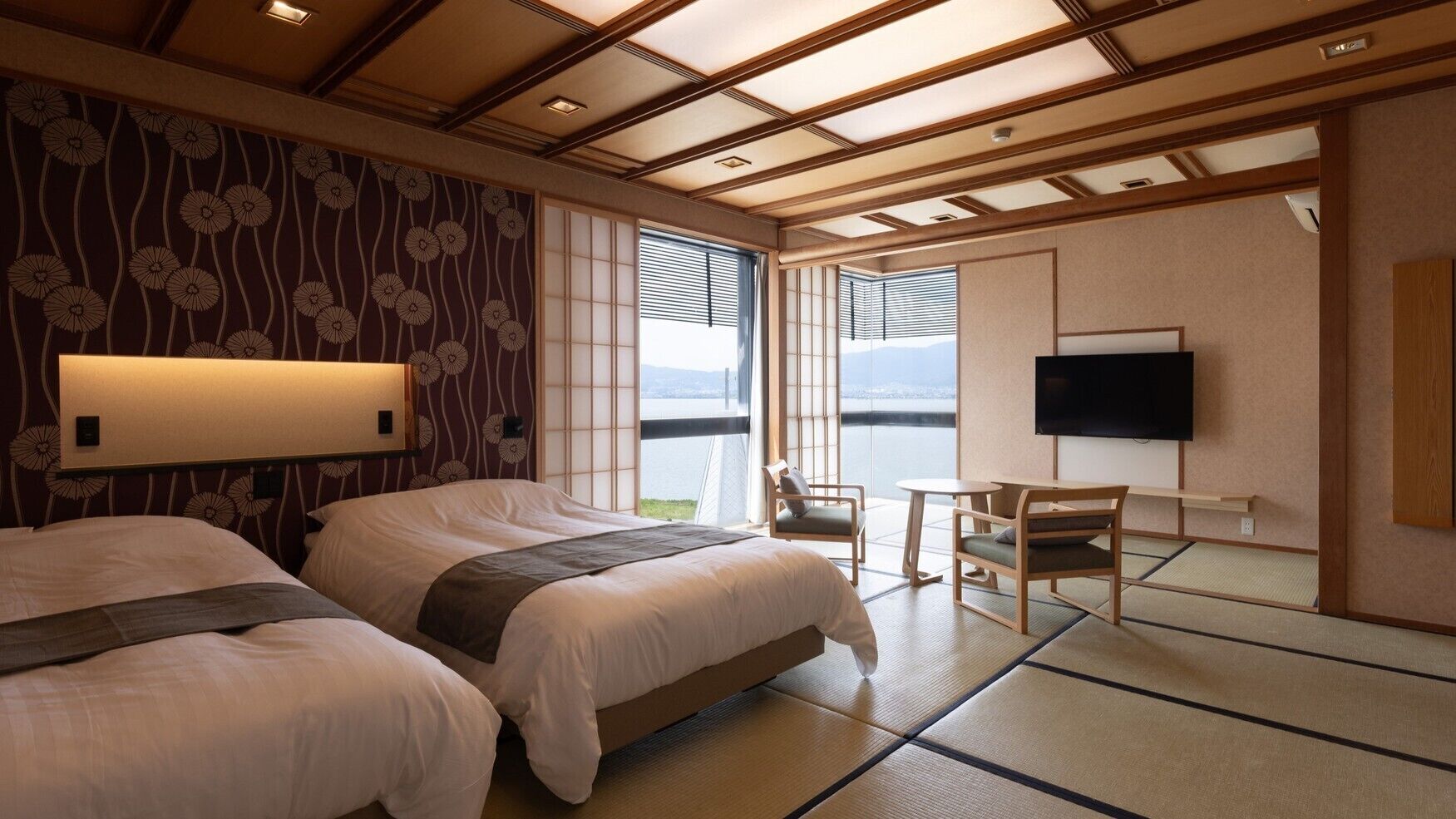 A hotel room with two beds, a TV, a small table, and a chair.