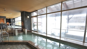 An indoor swimming pool with clear glass windows, a tiled floor, and a metal staircase leading into the pool. - Rako Hananoi Hotel (Suwa)