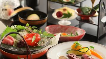 A variety of dishes including sashimi, vegetables, and meat, arranged on a table.