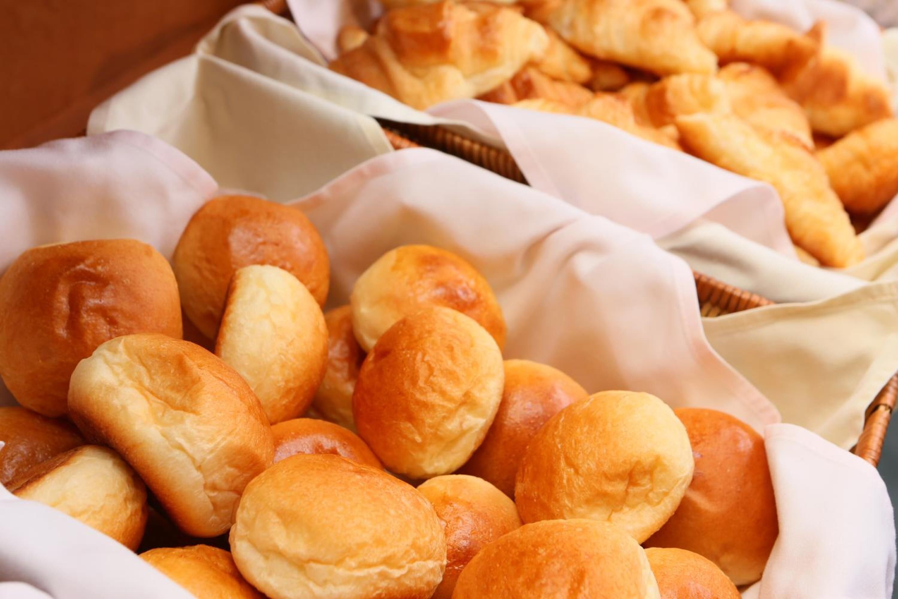 A basket filled with golden-brown dinner rolls.